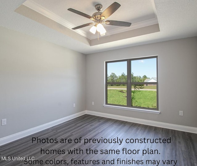 spare room with crown molding, ceiling fan, a tray ceiling, and dark hardwood / wood-style flooring