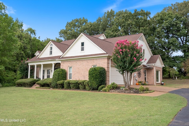 view of front of property featuring a front yard, covered porch, and a garage