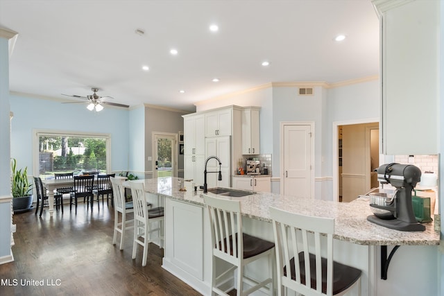 kitchen featuring light stone counters, decorative backsplash, sink, and a kitchen bar