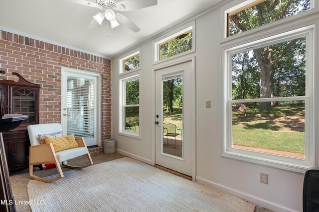 entryway with ceiling fan, light carpet, a wealth of natural light, and brick wall