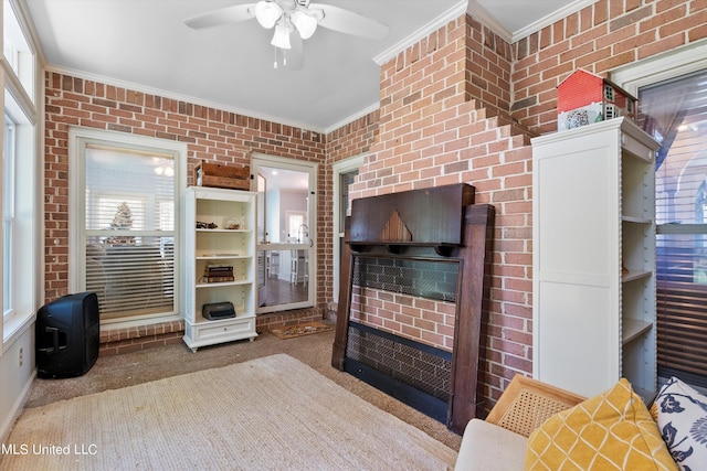 carpeted living room featuring ceiling fan, brick wall, and ornamental molding