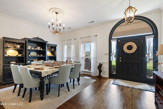 dining area featuring dark wood-type flooring, ornamental molding, and a chandelier