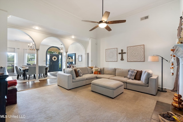 living room with crown molding, ceiling fan with notable chandelier, and light wood-type flooring