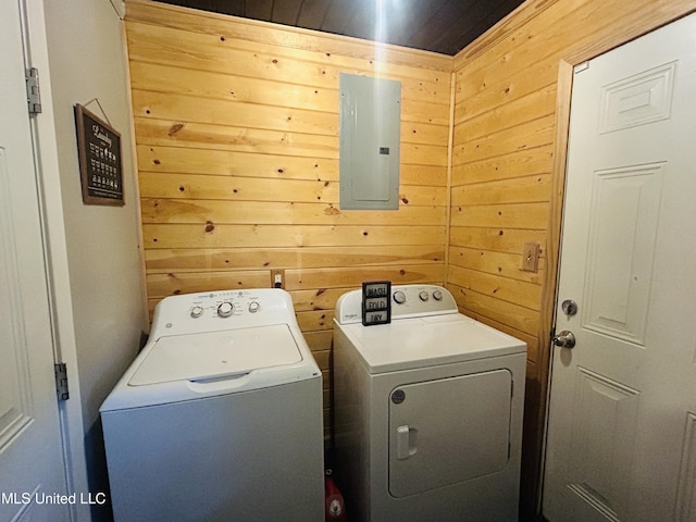 washroom with electric panel, separate washer and dryer, and wood walls