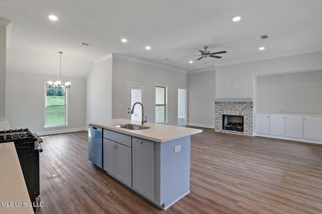 kitchen featuring stainless steel dishwasher, sink, a fireplace, gray cabinets, and an island with sink