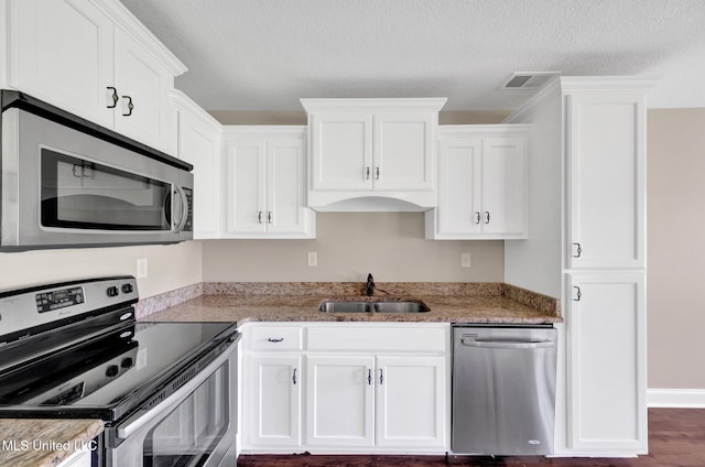 2338 Khushboo Cv, Southaven, MS 38671 - kitchen featuring appliances with stainless steel finishes, white cabinetry, a textured ceiling, wood finished floors, and light stone counters