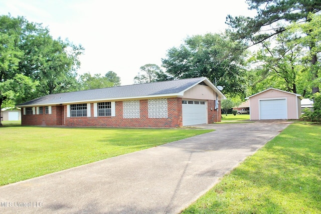 single story home with brick siding, a garage, a front lawn, and an outbuilding
