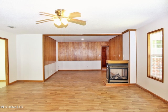 unfurnished living room featuring visible vents, light wood-style floors, baseboards, a ceiling fan, and a multi sided fireplace