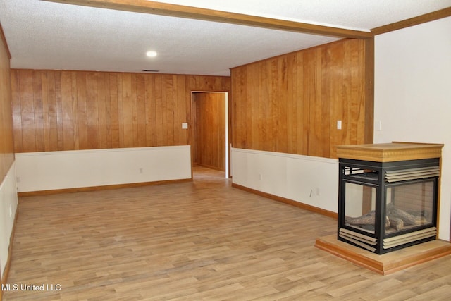 interior space featuring wooden walls, a textured ceiling, and wood finished floors