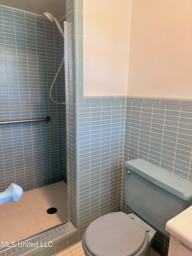 full bath featuring a wainscoted wall, a stall shower, toilet, and tile walls