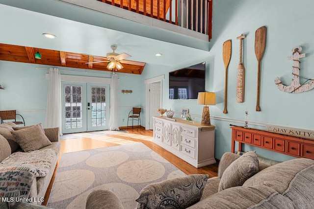 living room featuring french doors, ceiling fan, light hardwood / wood-style floors, and beamed ceiling