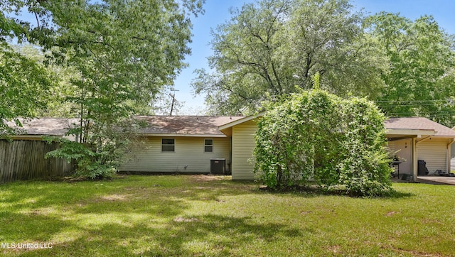 back of property with fence, a yard, and central AC