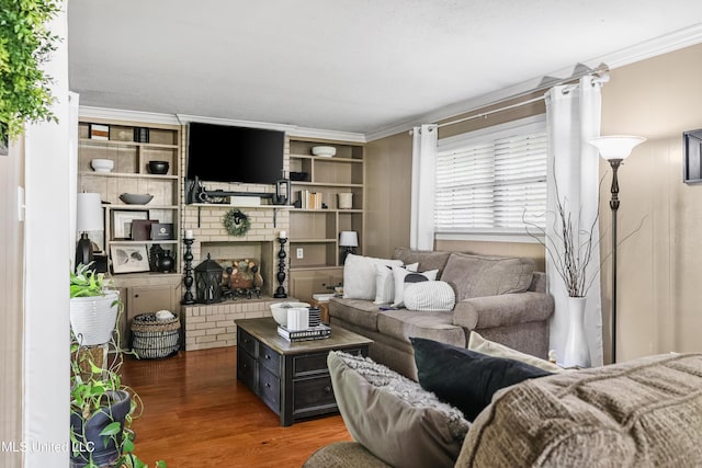 living area featuring built in shelves, ornamental molding, and wood finished floors