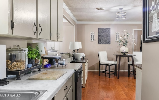 kitchen featuring light countertops, light wood-style floors, a textured ceiling, and crown molding