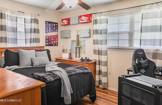 bedroom featuring wood finished floors, a ceiling fan, and baseboards