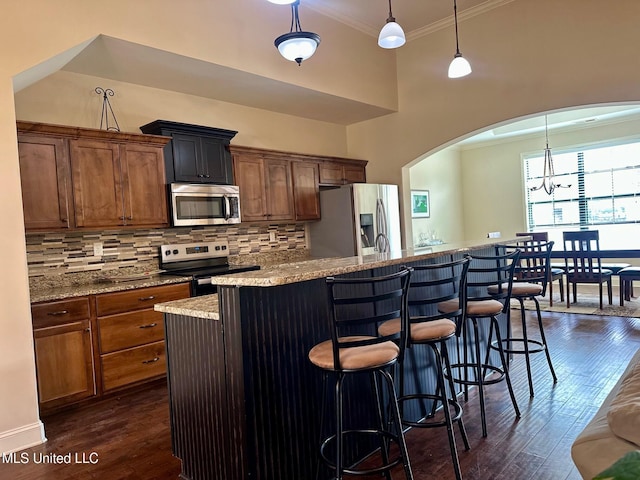 kitchen featuring pendant lighting, stainless steel appliances, dark hardwood / wood-style flooring, and a breakfast bar area