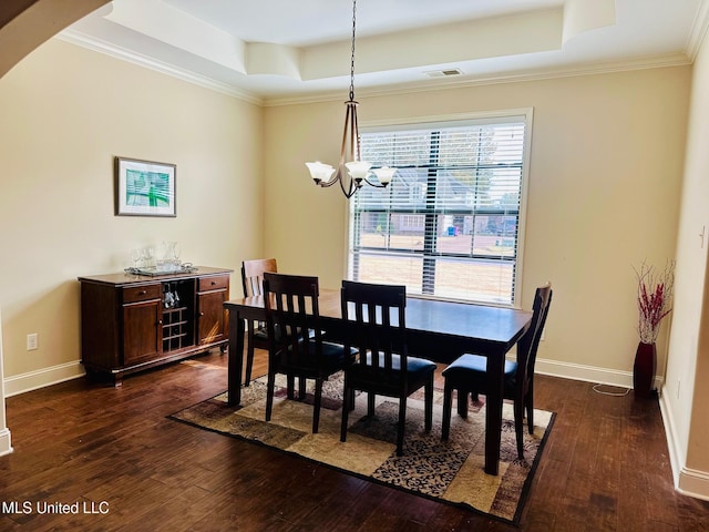 dining room with dark hardwood / wood-style floors, a tray ceiling, an inviting chandelier, and crown molding