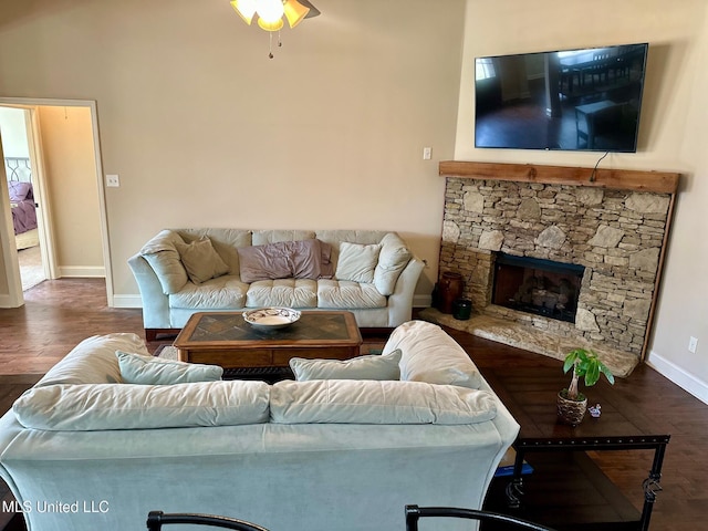 living room featuring a stone fireplace and dark wood-type flooring