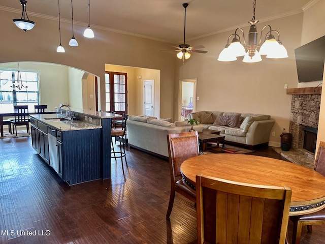 kitchen featuring dark hardwood / wood-style floors, pendant lighting, a fireplace, sink, and a kitchen island with sink