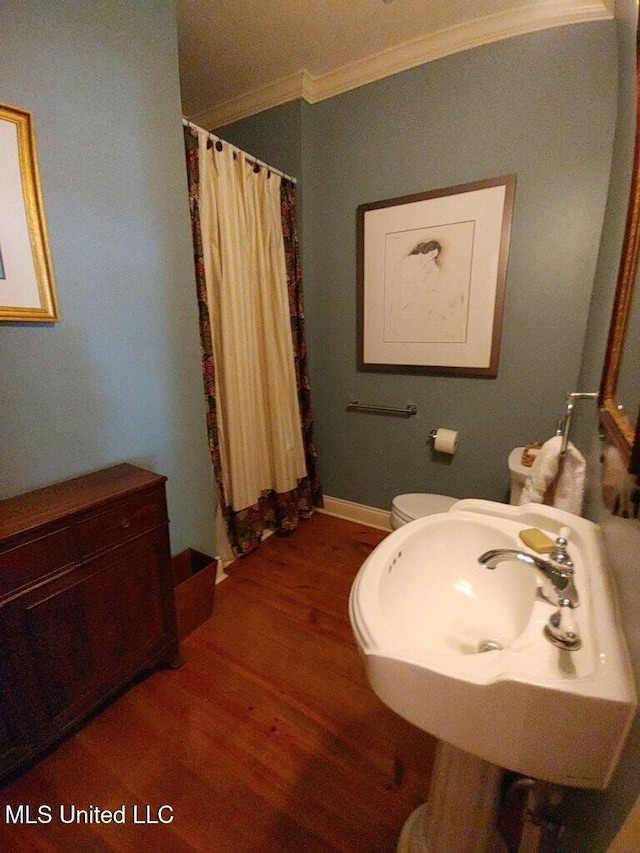 full bathroom featuring curtained shower, toilet, ornamental molding, wood finished floors, and a sink