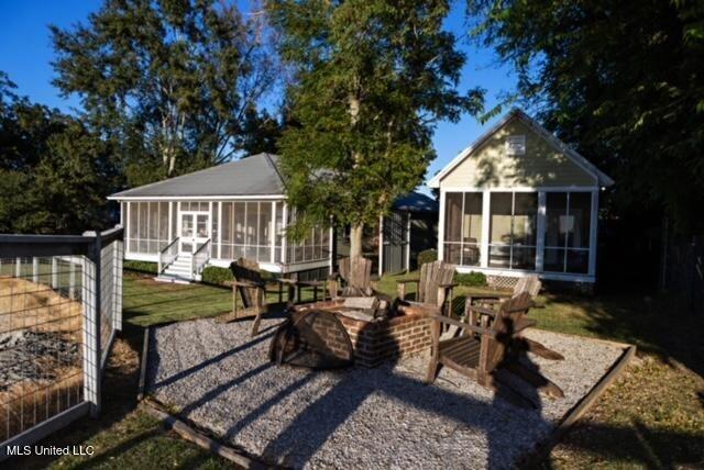 back of house with an outdoor fire pit and a sunroom