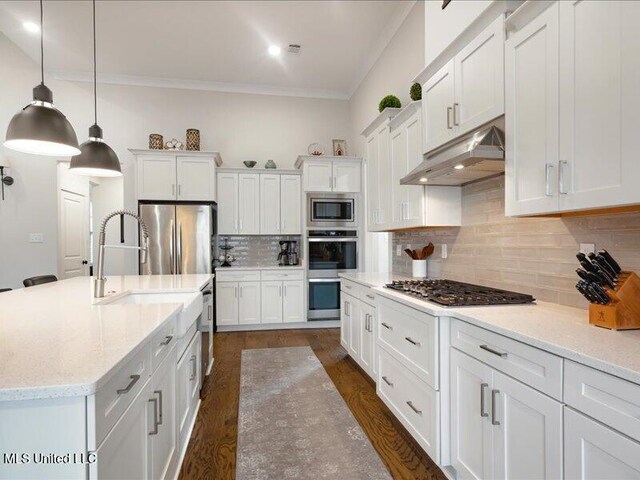 kitchen with light stone countertops, appliances with stainless steel finishes, backsplash, pendant lighting, and white cabinets