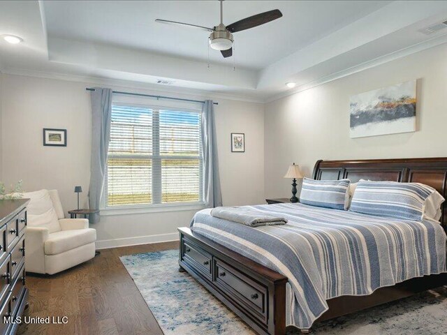 bedroom featuring a raised ceiling, ceiling fan, dark hardwood / wood-style flooring, and crown molding