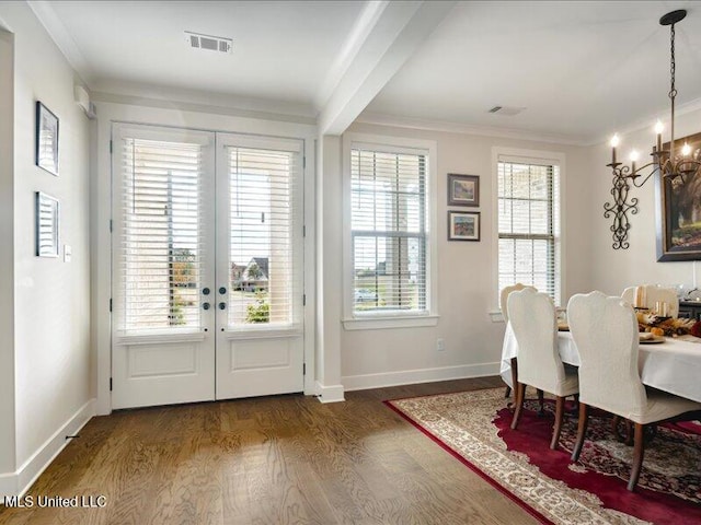 dining area with an inviting chandelier, crown molding, dark wood-type flooring, and french doors