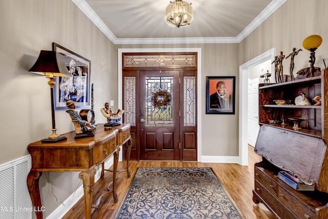 entrance foyer with visible vents, ornamental molding, wood finished floors, an inviting chandelier, and baseboards