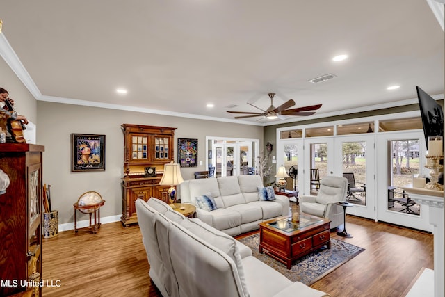 living area with french doors, wood finished floors, visible vents, and ornamental molding