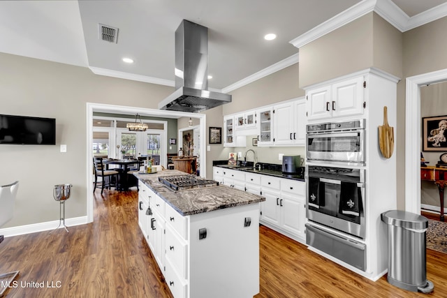 kitchen with visible vents, a center island, island range hood, stainless steel appliances, and a warming drawer