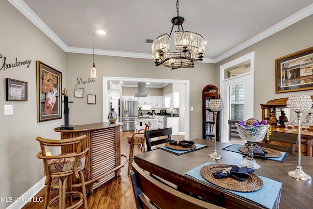 dining space with visible vents, wood finished floors, crown molding, baseboards, and a chandelier