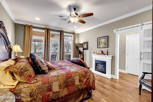 bedroom featuring a barn door, baseboards, light wood-style flooring, and crown molding