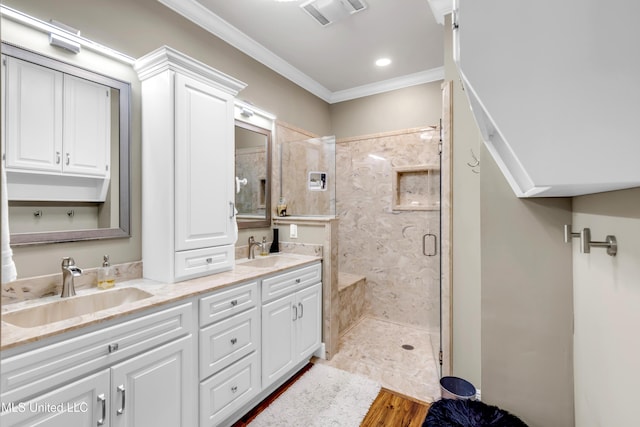 bathroom featuring visible vents, double vanity, ornamental molding, a sink, and a shower stall