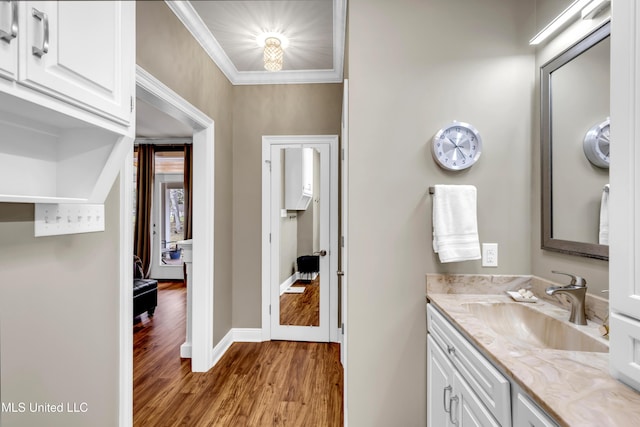 bathroom featuring wood finished floors, vanity, baseboards, and ornamental molding
