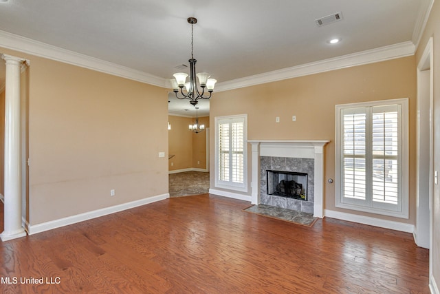 unfurnished living room featuring hardwood / wood-style flooring, a wealth of natural light, a notable chandelier, and a tiled fireplace