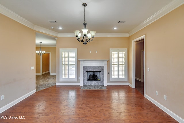 unfurnished living room featuring dark hardwood / wood-style floors, ornamental molding, a premium fireplace, and an inviting chandelier