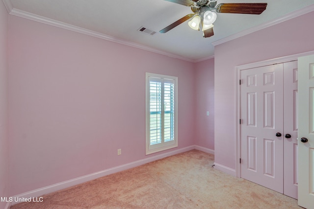 unfurnished bedroom featuring ceiling fan, light colored carpet, ornamental molding, and a closet