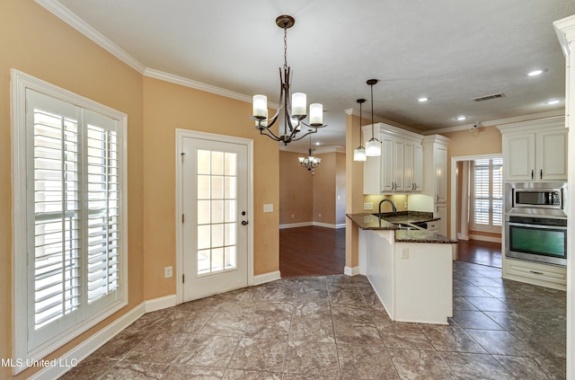 kitchen featuring kitchen peninsula, appliances with stainless steel finishes, sink, dark stone countertops, and hanging light fixtures