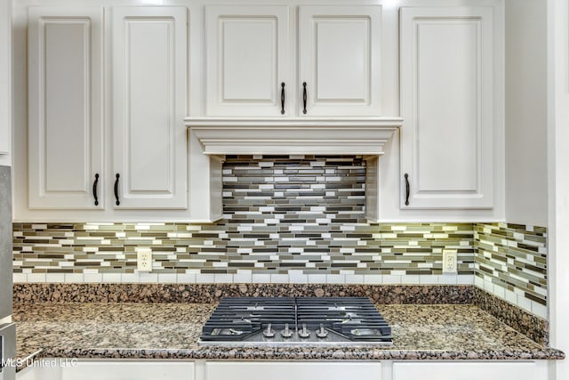 details with tasteful backsplash, dark stone counters, custom exhaust hood, white cabinets, and stainless steel gas stovetop