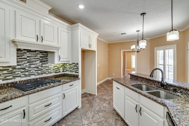 kitchen featuring sink, dark stone countertops, appliances with stainless steel finishes, decorative light fixtures, and white cabinetry