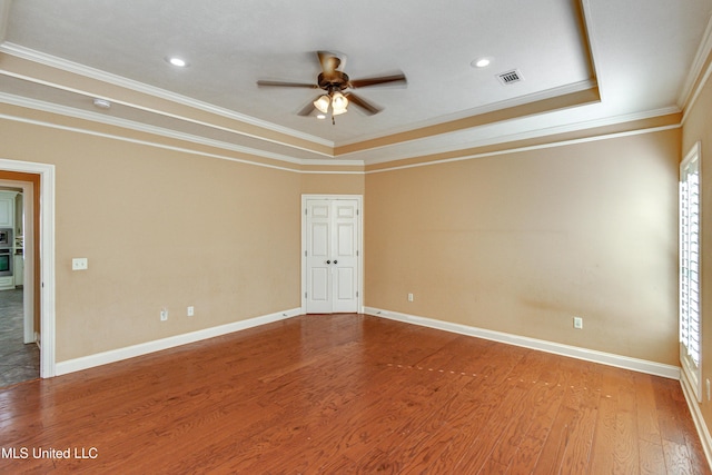 unfurnished room with a tray ceiling, ceiling fan, wood-type flooring, and ornamental molding