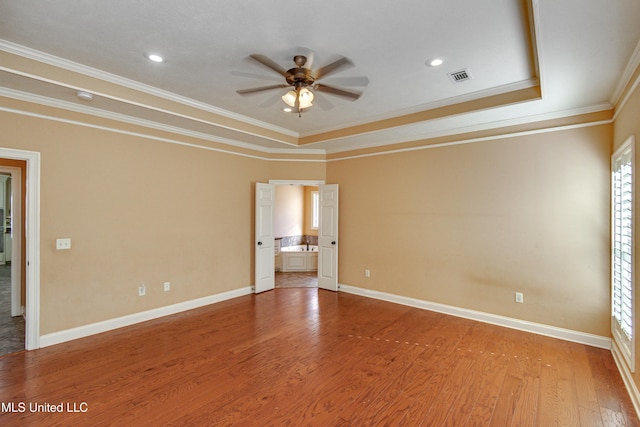 spare room with hardwood / wood-style floors, a tray ceiling, ceiling fan, and ornamental molding