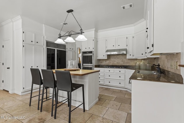 13 Highland Meadows Dr, Jackson, MS 39211 - kitchen with paneled refrigerator, white cabinetry, under cabinet range hood, stainless steel double oven, and decorative backsplash