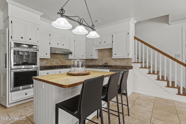 13 Highland Meadows Dr, Jackson, MS 39211 - kitchen with butcher block counters, double oven, under cabinet range hood, ornamental molding, and decorative backsplash