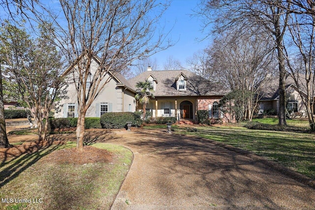 view of front of house featuring stucco siding, a chimney, and a front yard