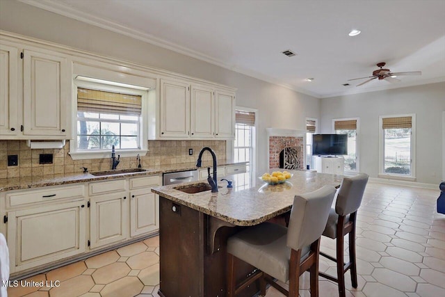 kitchen with a wealth of natural light, visible vents, ornamental molding, a sink, and backsplash