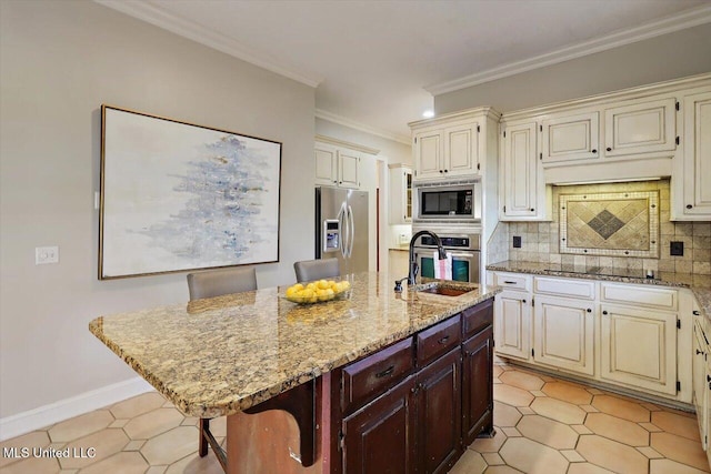 kitchen featuring tasteful backsplash, crown molding, light stone counters, stainless steel appliances, and a kitchen island with sink