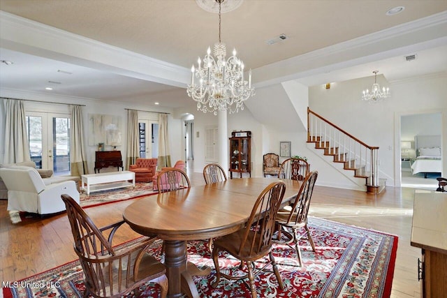 dining area with crown molding, stairway, light wood-style flooring, and visible vents