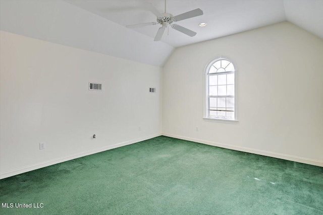 carpeted spare room with visible vents, baseboards, ceiling fan, and vaulted ceiling